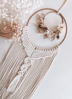 a white dream catcher with dried flowers and feathers on the top, next to it