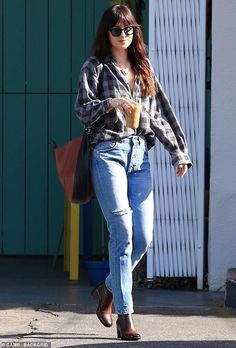 a woman walking down the street with a cup in her hand