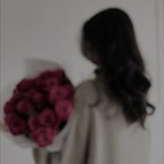 a blurry photo of a woman holding a bouquet of red roses in her hand