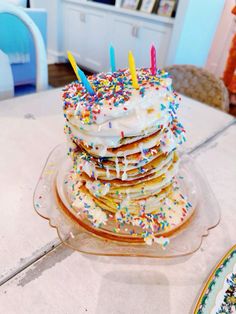 a stack of pancakes covered in frosting and sprinkles with lit candles