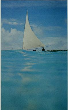 a sailboat in the middle of the ocean with blue sky and clouds behind it