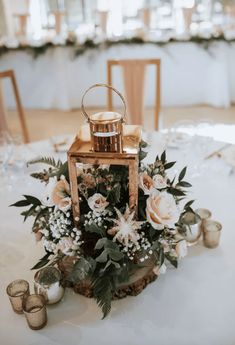 a table with candles, flowers and a small lantern on it's centerpiece