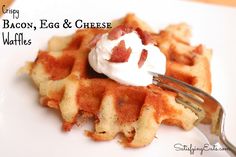 bacon, egg and cheese waffles on a white plate with a fork in it