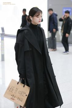 a woman in black coat carrying shopping bags