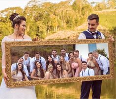 a bride and groom holding up a photo with their wedding party in front of them