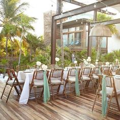 tables and chairs are set up on the deck for an outdoor wedding reception in tropical setting