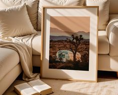 an open book sitting on top of a floor next to a couch and a framed photo