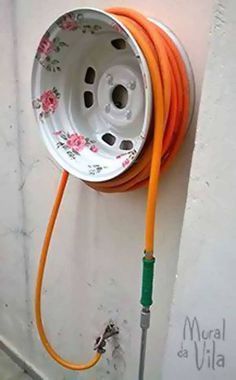 an orange hose attached to a white wall next to a metal spigot with flowers on it