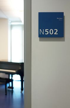 there is a blue sign that says n502 next to a piano in an empty room