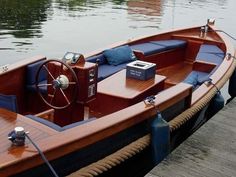 a wooden boat docked at a dock with the steering wheel on it's side