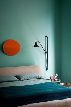 a bedroom with green walls and an orange circle on the wall