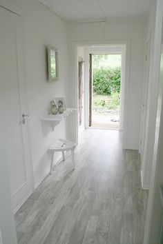 an empty hallway with white walls and wood flooring is seen in this image from the front door