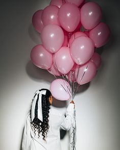 a woman holding pink balloons in her hand