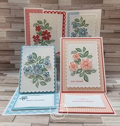 three cards with flowers on them sitting on top of a wooden table next to each other