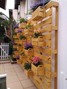 several wooden planters are lined up on the side of a building with flowers in them