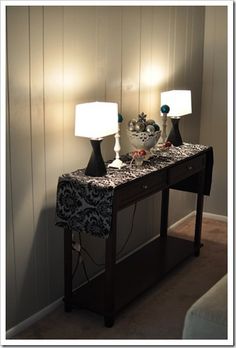 two lamps sitting on top of a wooden table next to a lamp shade and wall