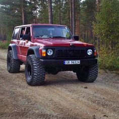 a red jeep driving down a dirt road