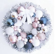 a christmas wreath with ornaments hanging from it's sides and a bow on top