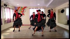 a group of women in black and white polka dot dresses dancing on a dance floor