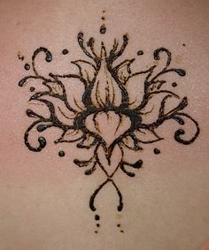 the back of a woman's neck with an intricate tattoo design on her chest