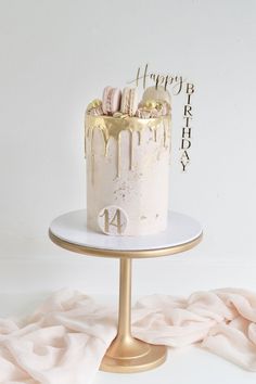 a birthday cake with white frosting and gold sprinkles on a stand