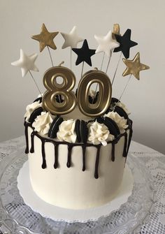 a white cake with chocolate icing and stars on top, decorated with the number 80