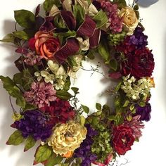 a wreath with flowers and leaves is hanging on the wall