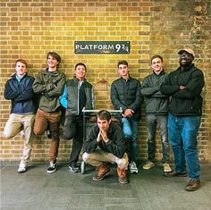 a group of men standing in front of a brick wall with a sign that says platform 94