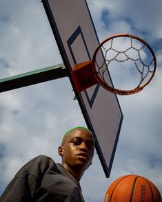 a young man standing next to a basketball hoop