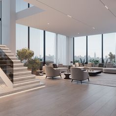 a living room filled with lots of furniture and tall windows next to a stair case