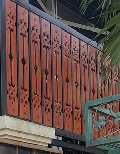 the side of a building that has red and black designs on it, with a palm tree in front of it