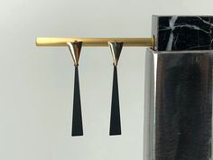 This stunning pair of geometric earrings features two triangles in beautiful contrasted colors and opposite alignment. The inverted triangle earring hooks in shinny gold on the top integrate the slim black triangles flawlessly into a sleek geometric simplicity with sophisticated appeal. It is a perfect gift for any minimalist with a refined taste! The triangle earring hooks are made of 18K gold plated brass. The posts are made of 925 sterling silver for sensitive ears. The earrings is 55mm (2.15 Modern Triangle Earrings For Party, Modern Black Geometric Earrings, Modern Triangle Party Earrings, Minimalist Geometric Earrings For Party, Modernist Black Earrings For Gift, Modernist Black Earrings As Gift, Modern Black Triangle Jewelry, Double Triangle, Black Drop Earrings