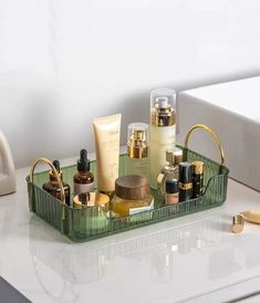 a green tray with various beauty products on top of a white counter next to a sink