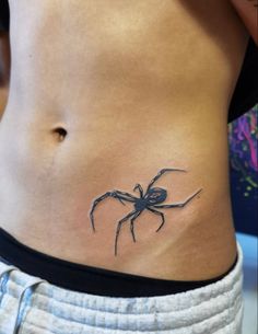 a woman's stomach with a spider tattoo on it