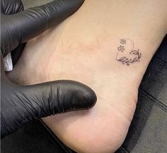 a small tattoo on the foot of a person with black gloves and rubber gloves around their feet