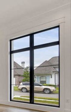 an empty living room with large windows looking out onto the street and cars parked in the driveway