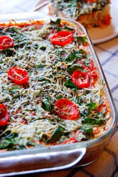 a casserole dish with spinach, tomatoes and cheese on the top is ready to be eaten