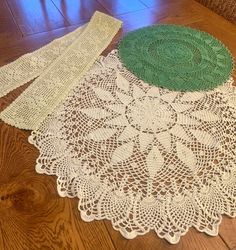 three doily on the floor with one green and white doily next to it