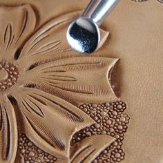 a close up of a spoon on top of a brown leather surface with flower designs