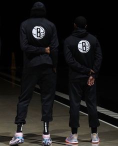 two men in black hoodies standing on the street