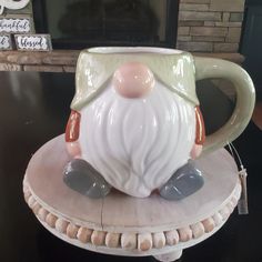 a ceramic coffee mug with a gnome's face on it sitting on a table