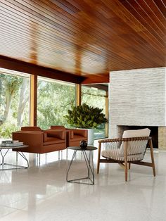 a living room filled with furniture next to a fire place under a wooden ceiling covered in windows