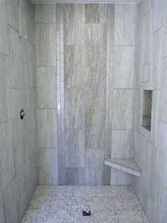 a walk in shower sitting next to a white tiled wall and floor with no door