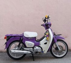 a purple and white motorcycle parked next to a pink wall