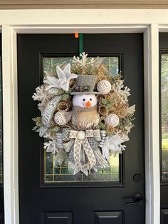 a christmas wreath with a snowman on it hanging from the front door, decorated with shells and seashells