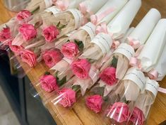 pink roses are wrapped in clear cellophane and placed on a wooden table top