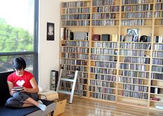 a person sitting on a couch in front of a bookshelf filled with dvds