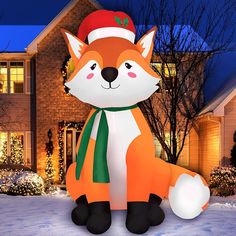 a large inflatable fox with a christmas hat and scarf sitting on the snow