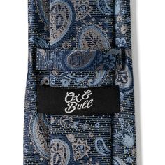 Stylish, silk, and very professional, this blue tie features a traditional paisley pattern woven in blue and gray threads. Floral motifs and gold pin dots enhance the design, elevating a classic look. This tie will maintain its shape and hold a perfect knot thanks to being crafted with durable yet soft 100% Silk. A versatile tie that can be added to any outfit and worn for both casual and formal occasions. Blue Paisley Print Business Ties, Blue Paisley Print Ties For Business, Blue Paisley Print Suit And Tie Accessories, Blue Paisley Print Tie For Black Tie Events, Blue Paisley Print Tie, Blue Paisley Print Standard Tie, Blue Paisley Print Ties For Black Tie Events, Blue Paisley Print Ties For Black Tie Occasion, Gold Pin