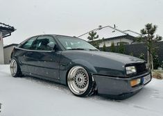 a gray car parked in the snow next to a house